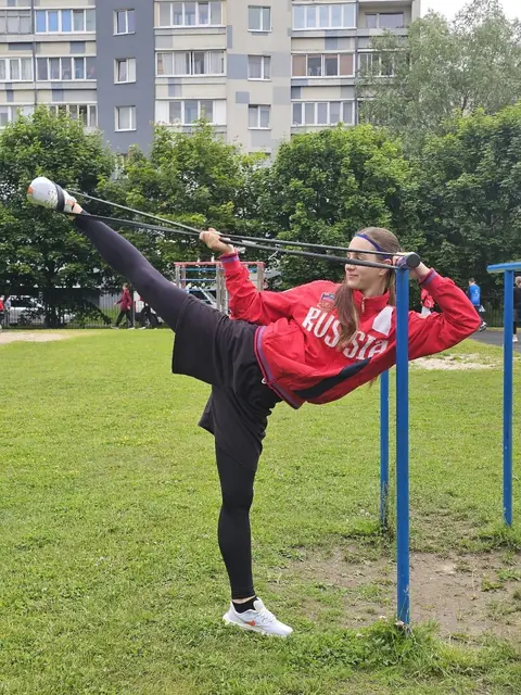 Спортсменка отрабатывает растяжку на открытом воздухе